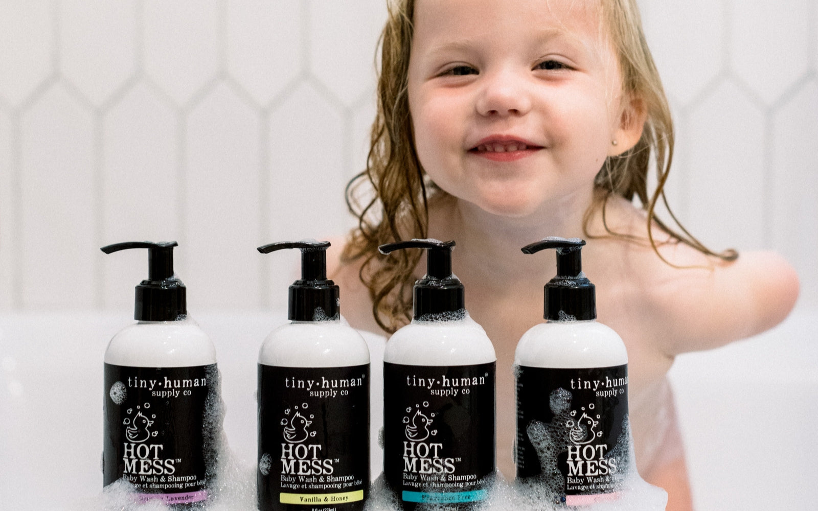 toddler with hot mess body wash and shampoo in bathtub with bubbles