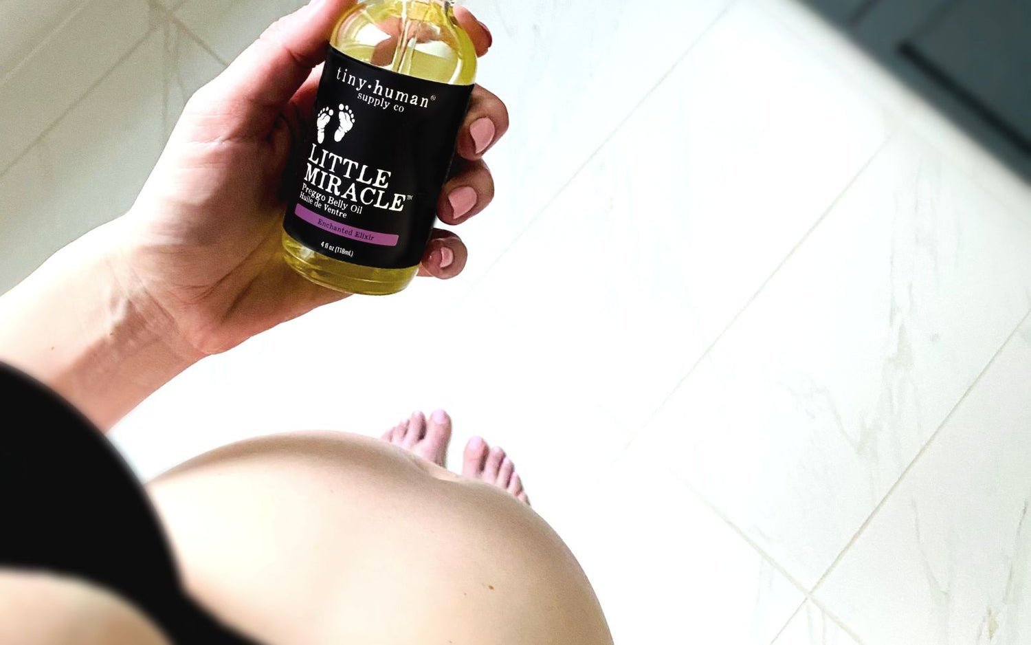 pregnant mom holding belly oil made by tiny human supply