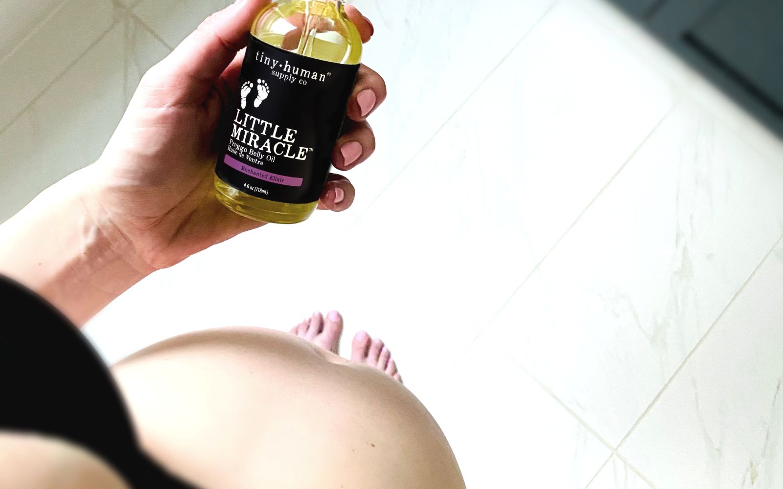 pregnant mom holding organic belly oil for stretch marks made by tiny human supply