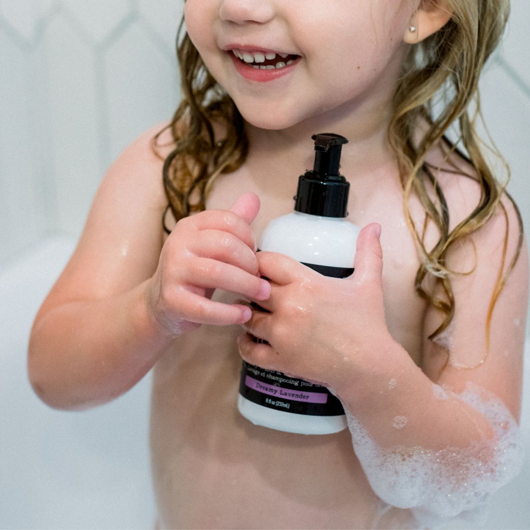 toddler holding body wash and shampoo during bath time with bubbles. 