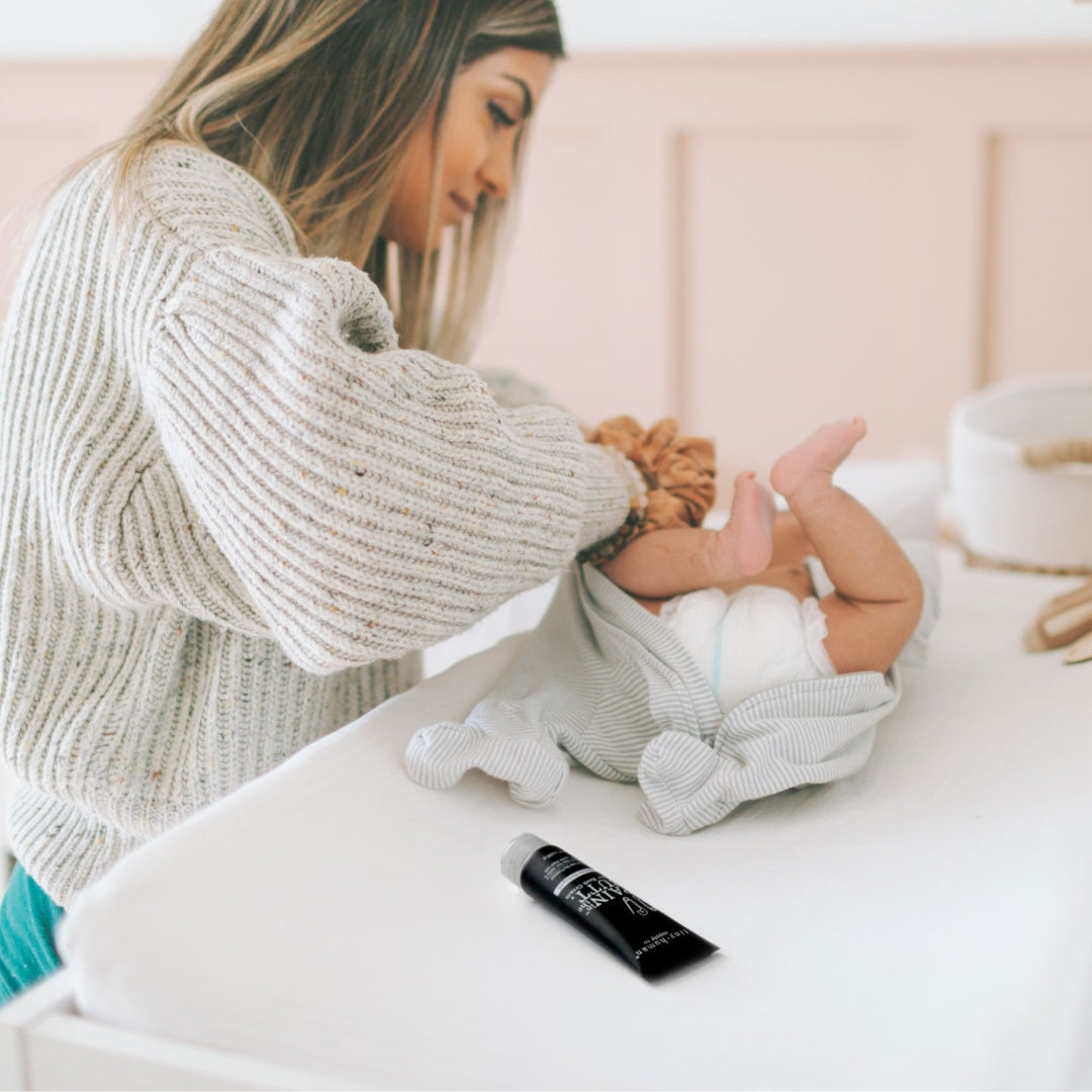 mom changing diaper with tiny human supply pain in the butt maximum strength diaper rash cream